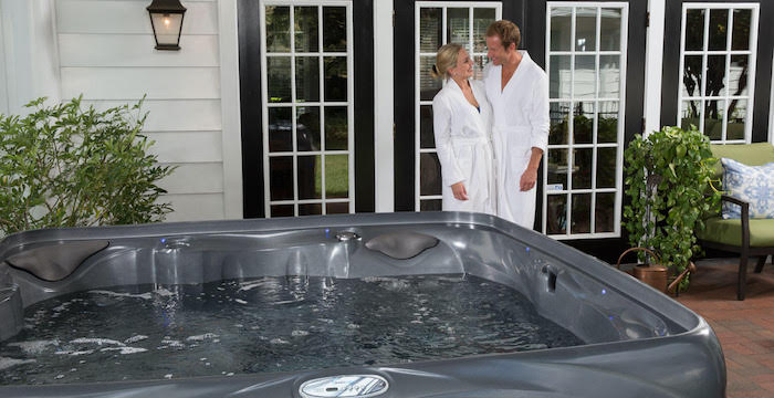 Happy couple in front of hot tub after learning the secret to easy spa care